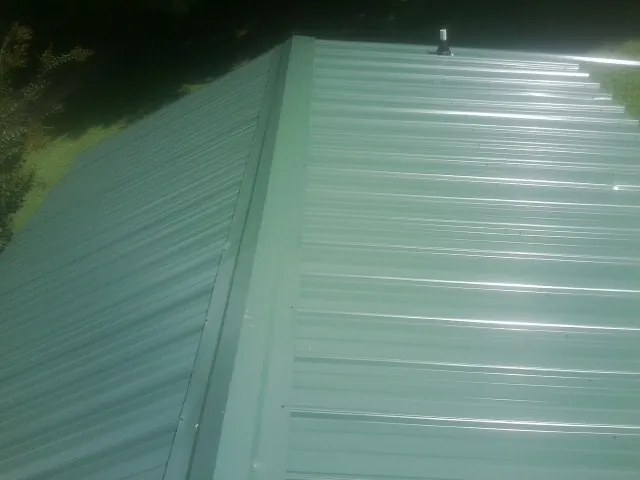 New green metal panels meeting at the ridge of a roof — Flat Roof Repair work by our crew in Bulls Gap
