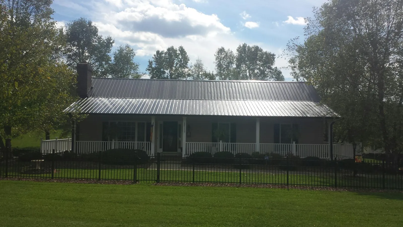 Gray metal roof on a brick ranch with a full width front porch — Gutter Guard Installation work by our crew in Bulls Gap