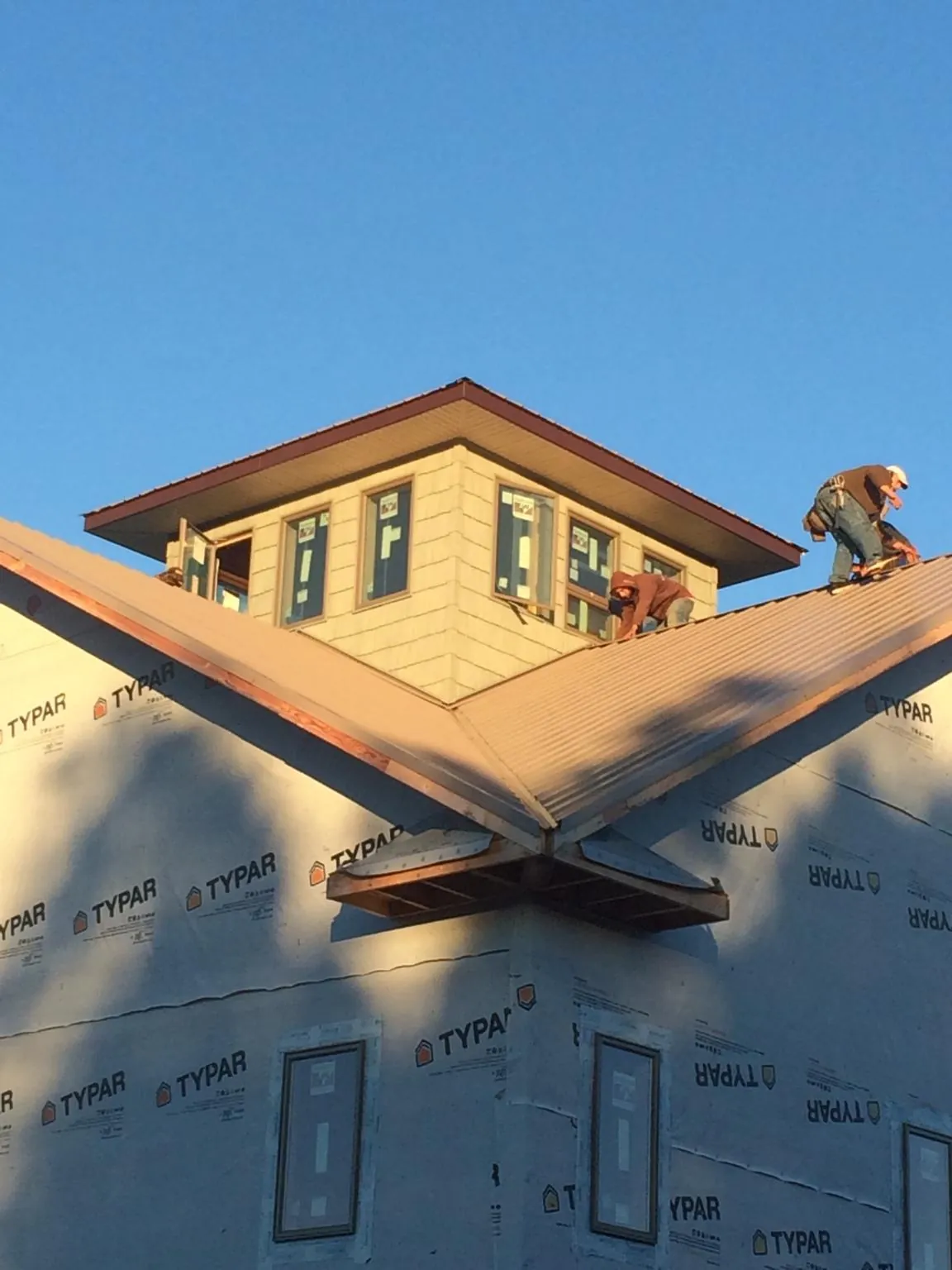 Roofers working around a rooftop cupola on a new metal roof at sunset — Roof Waterproofing in Bulls Gap by Roofing Brothers
